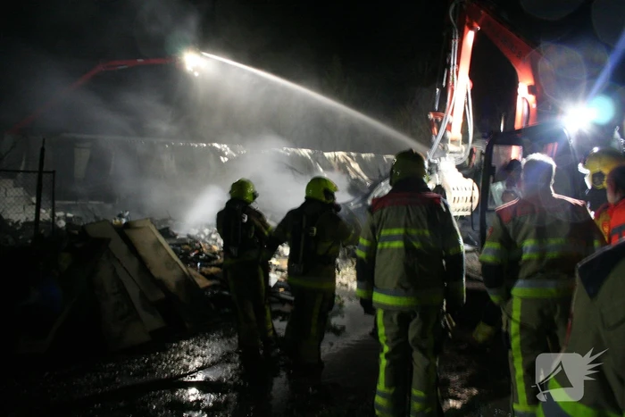 Grote uitslaande brand in loods achter woning
