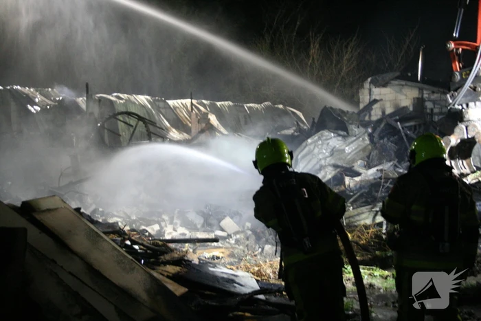 Grote uitslaande brand in loods achter woning