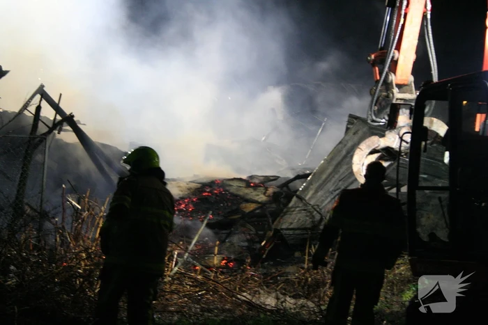 Grote uitslaande brand in loods achter woning