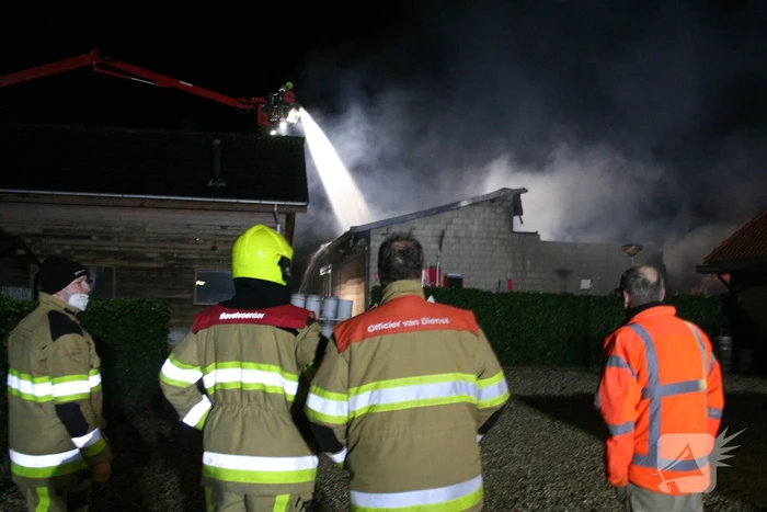 Grote uitslaande brand in loods achter woning