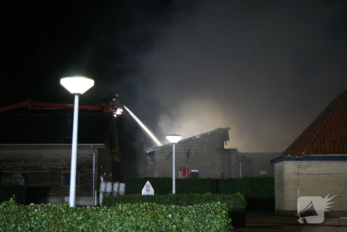 Grote uitslaande brand in loods achter woning