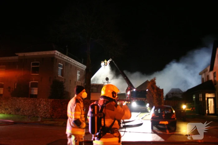 Grote uitslaande brand in loods achter woning