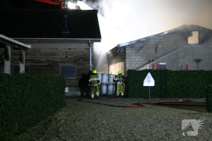 Grote uitslaande brand in loods achter woning