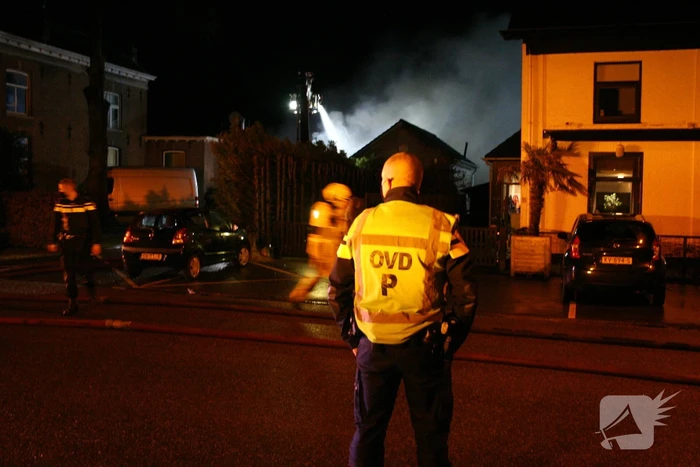 Grote uitslaande brand in loods achter woning