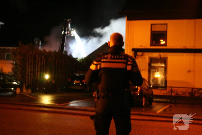Grote uitslaande brand in loods achter woning