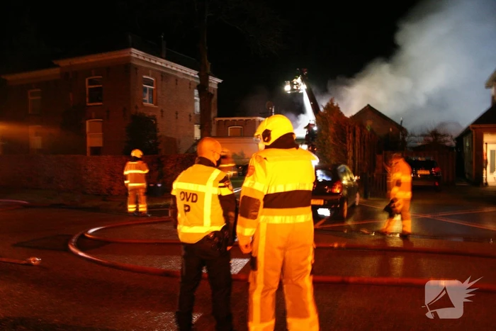 Grote uitslaande brand in loods achter woning
