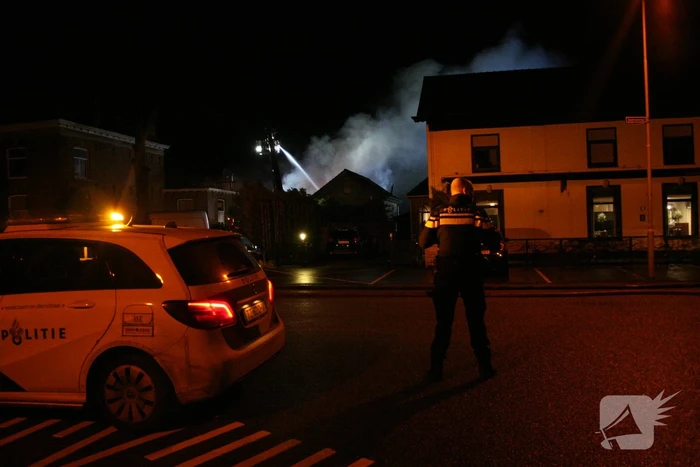 Grote uitslaande brand in loods achter woning