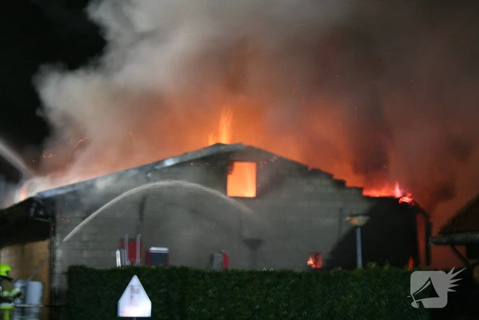 Grote uitslaande brand in loods achter woning