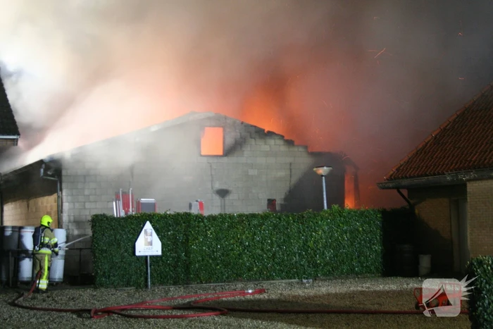 Grote uitslaande brand in loods achter woning