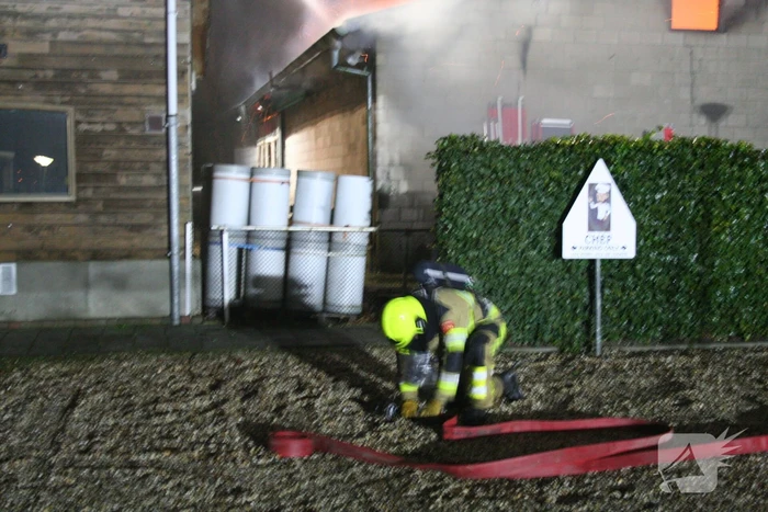 Grote uitslaande brand in loods achter woning