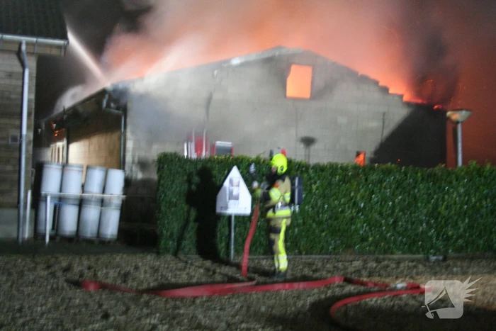 Grote uitslaande brand in loods achter woning