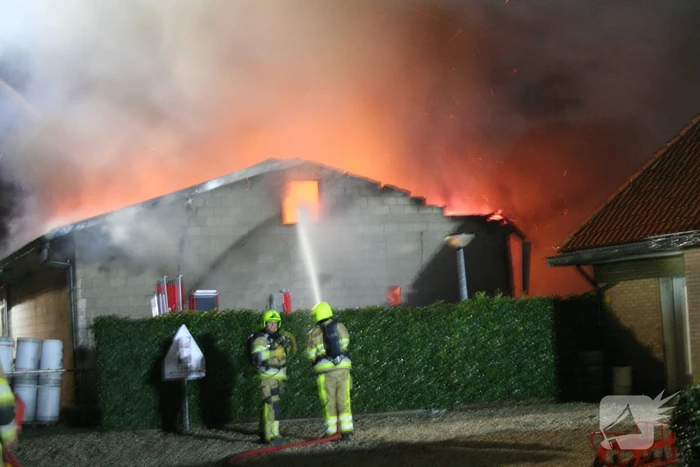 Grote uitslaande brand in loods achter woning