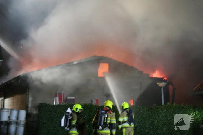 Grote uitslaande brand in loods achter woning