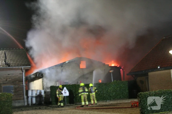 Grote uitslaande brand in loods achter woning