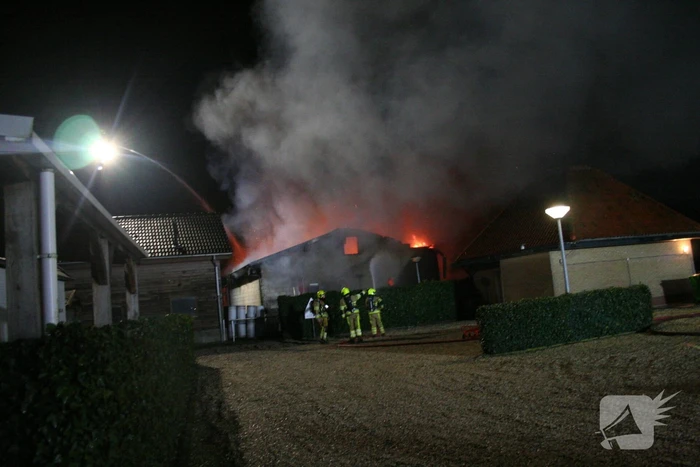 Grote uitslaande brand in loods achter woning