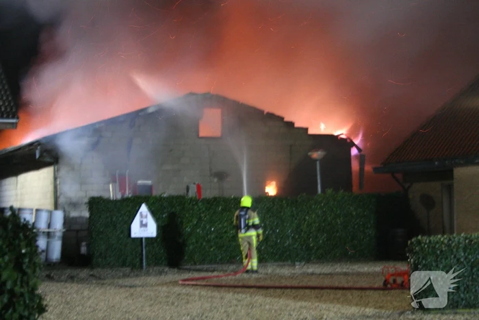 Grote uitslaande brand in loods achter woning