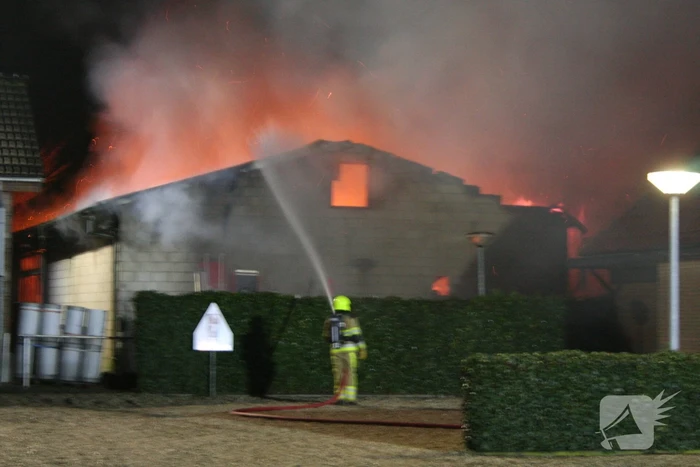 Grote uitslaande brand in loods achter woning