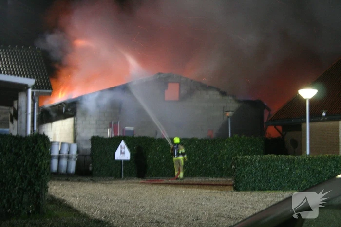 Grote uitslaande brand in loods achter woning