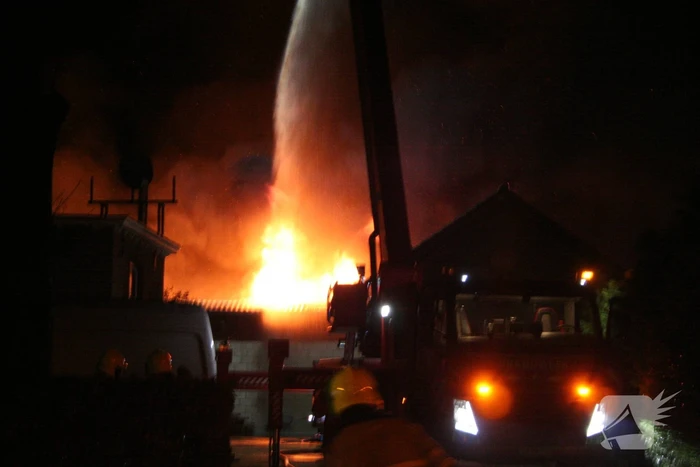 Grote uitslaande brand in loods achter woning