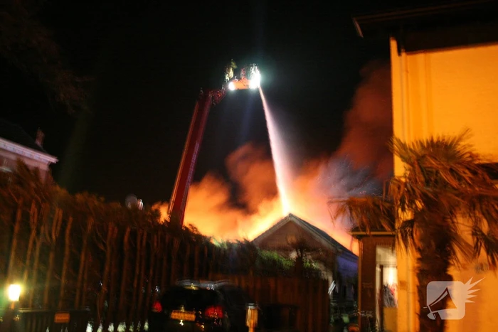 Grote uitslaande brand in loods achter woning