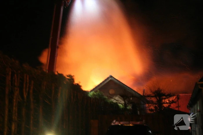 Grote uitslaande brand in loods achter woning