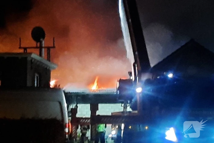 Grote uitslaande brand in loods achter woning