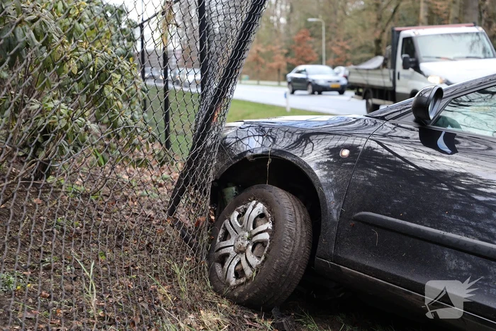 Auto eindigt aan overkant van de weg in hekwerk