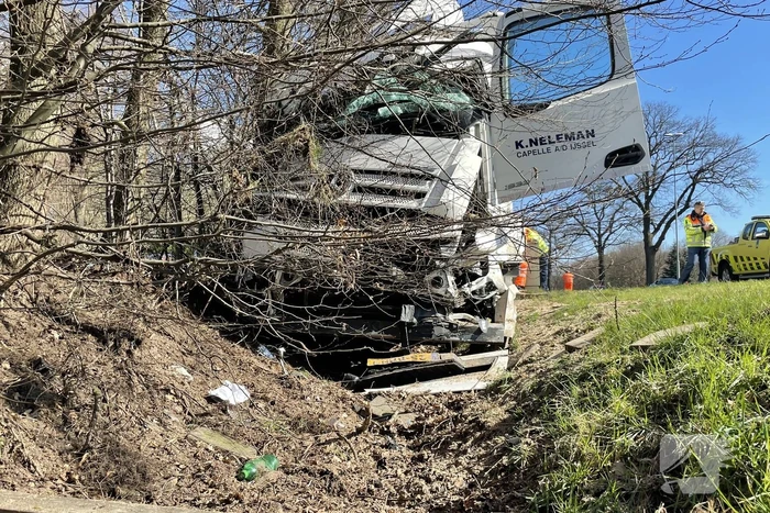 Vrachtwagen belandt in berm tegen boom