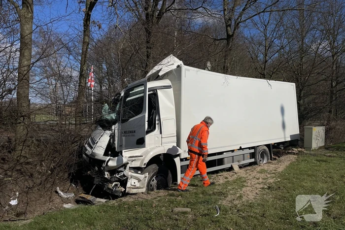 Vrachtwagen belandt in berm tegen boom