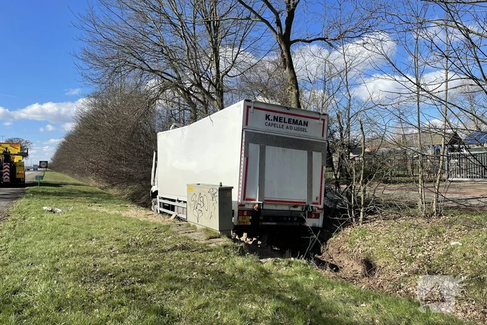 Vrachtwagen belandt in berm tegen boom