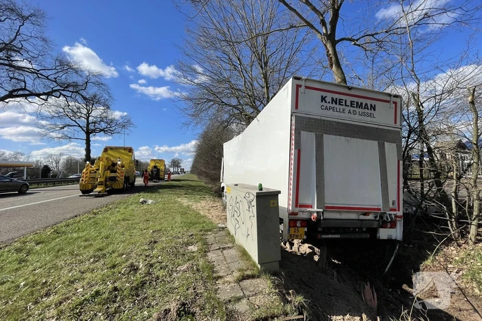 Vrachtwagen belandt in berm tegen boom