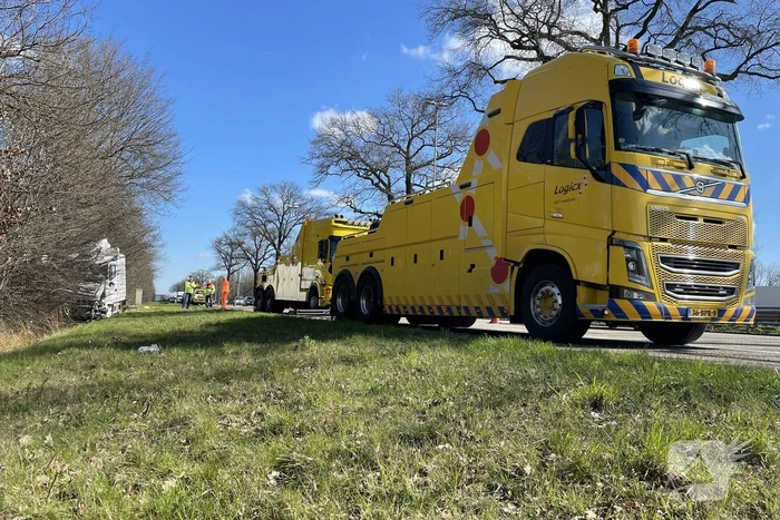 Vrachtwagen belandt in berm tegen boom