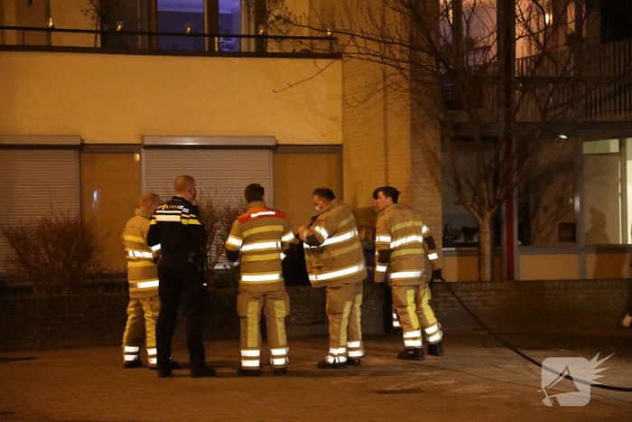 Brandweer blust brandende papiercontainer
