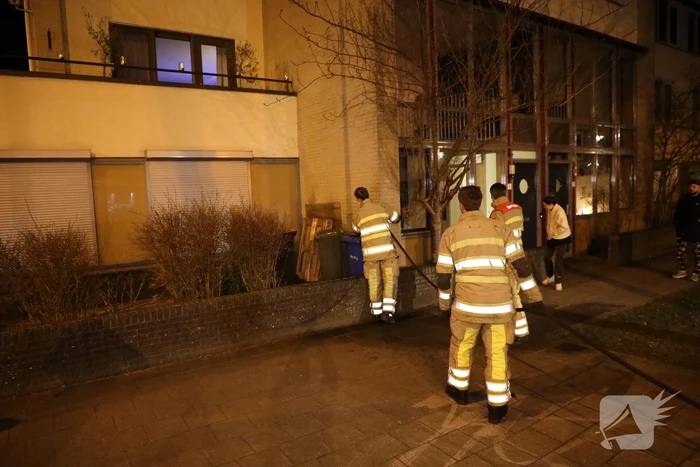 Brandweer blust brandende papiercontainer