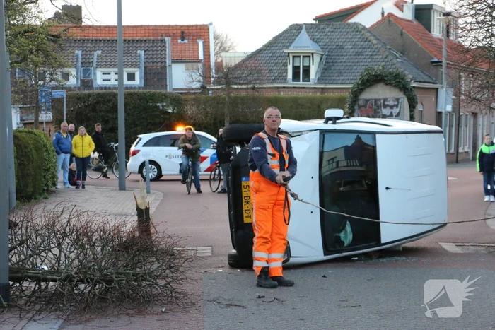 Busje op zijn kant na botsing met boom