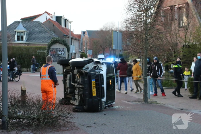 Busje op zijn kant na botsing met boom