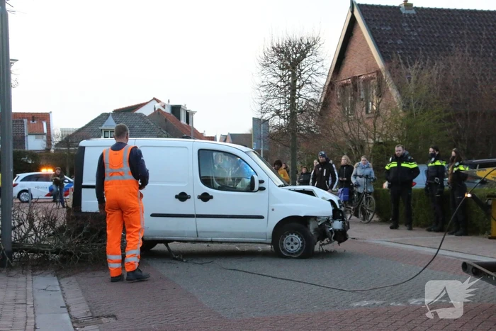 Busje op zijn kant na botsing met boom