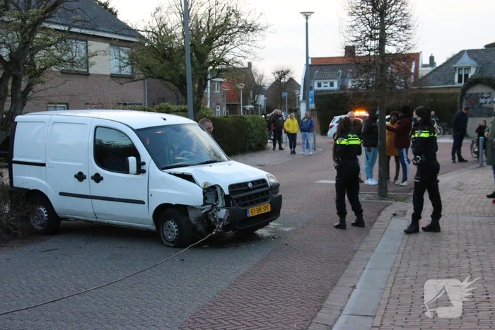 Busje op zijn kant na botsing met boom