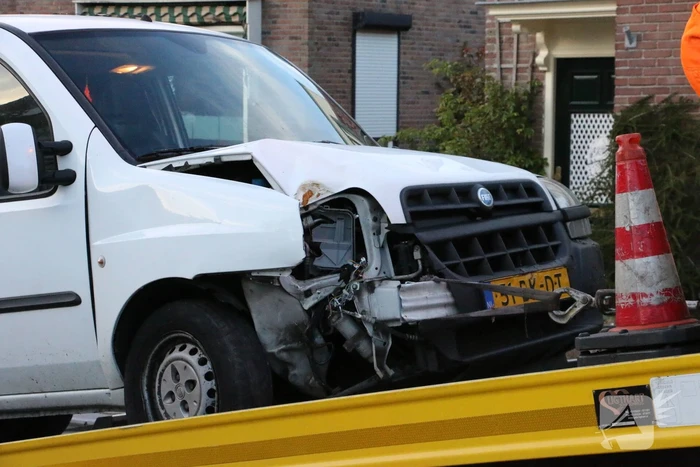 Busje op zijn kant na botsing met boom