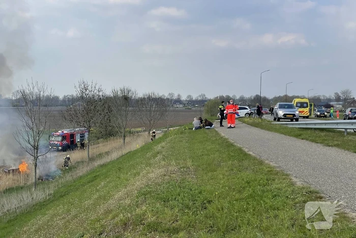 Auto glijdt van dijk af na botsing en vliegt in brand