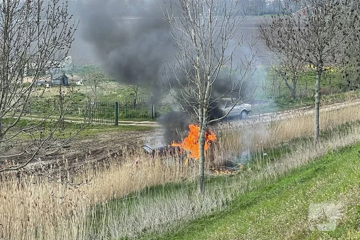 Auto glijdt van dijk af na botsing en vliegt in brand