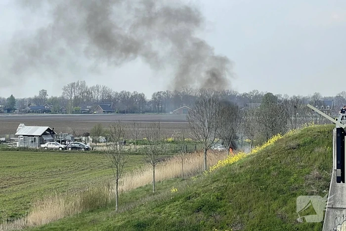 Auto glijdt van dijk af na botsing en vliegt in brand
