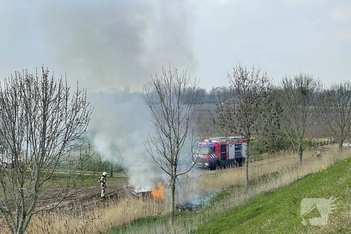 Auto glijdt van dijk af na botsing en vliegt in brand