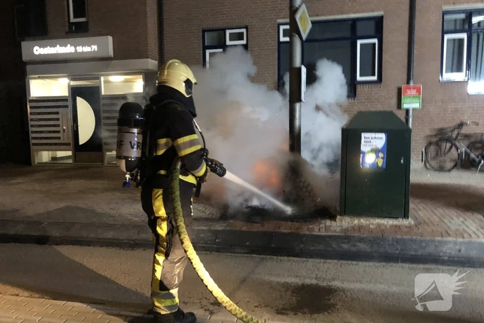 Houtstapel in brand naast container