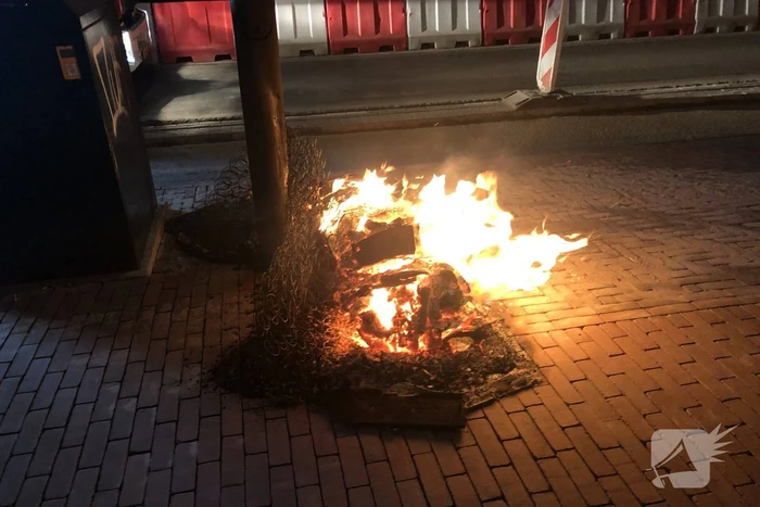 Houtstapel in brand naast container