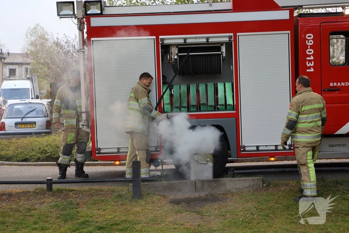 Brandweer blust brand in afvalcontainer