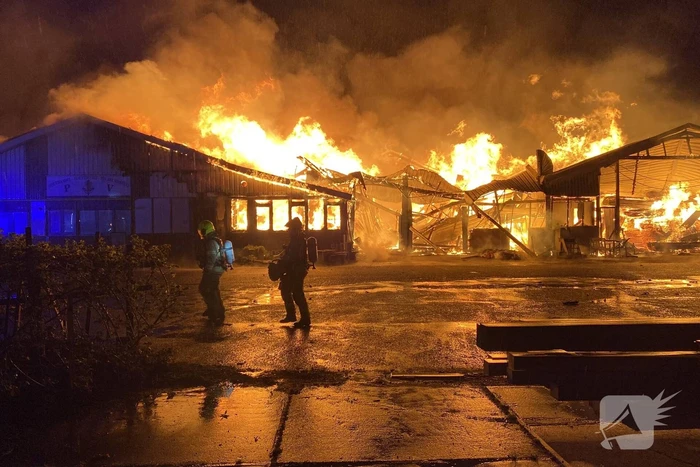 Brandweer bestrijdt grote uitslaande brand in twee loodsen