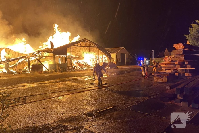 Brandweer bestrijdt grote uitslaande brand in twee loodsen