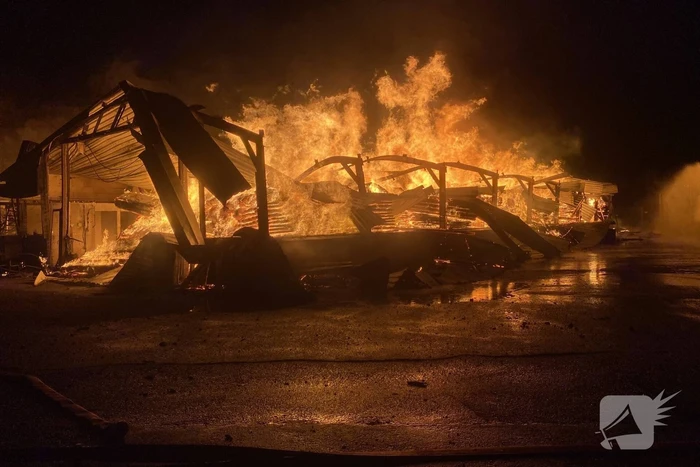 Brandweer bestrijdt grote uitslaande brand in twee loodsen