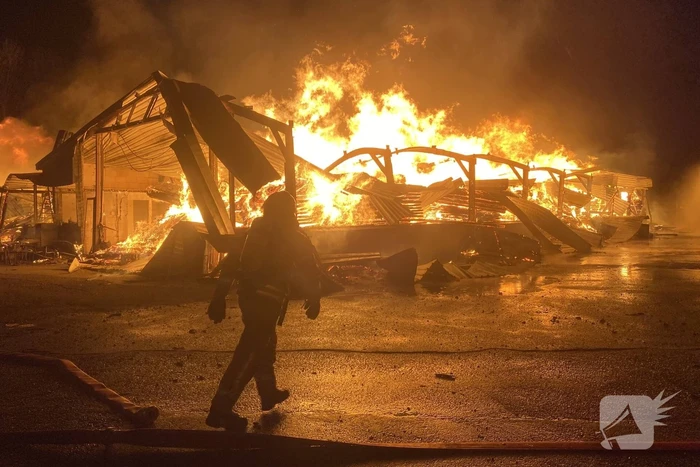 Brandweer bestrijdt grote uitslaande brand in twee loodsen